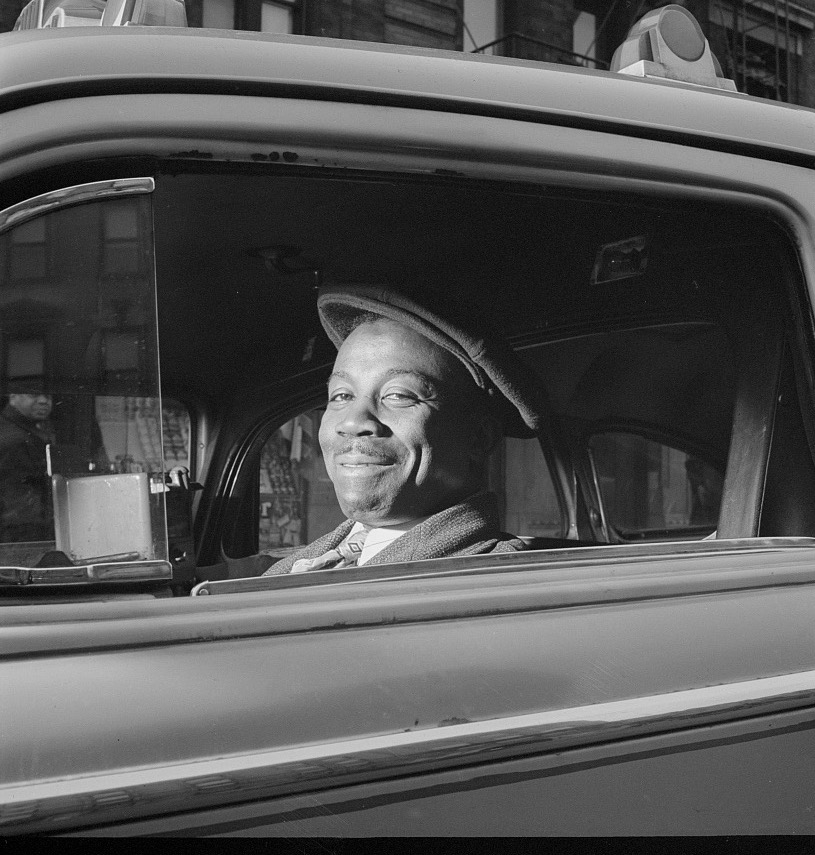 Smiling New York taxi driver leaning out his cab window, 1942