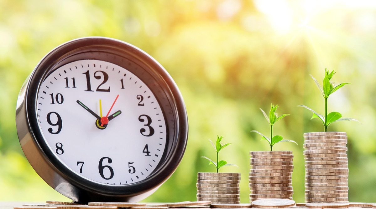 A clock beside growing stacks of coins
