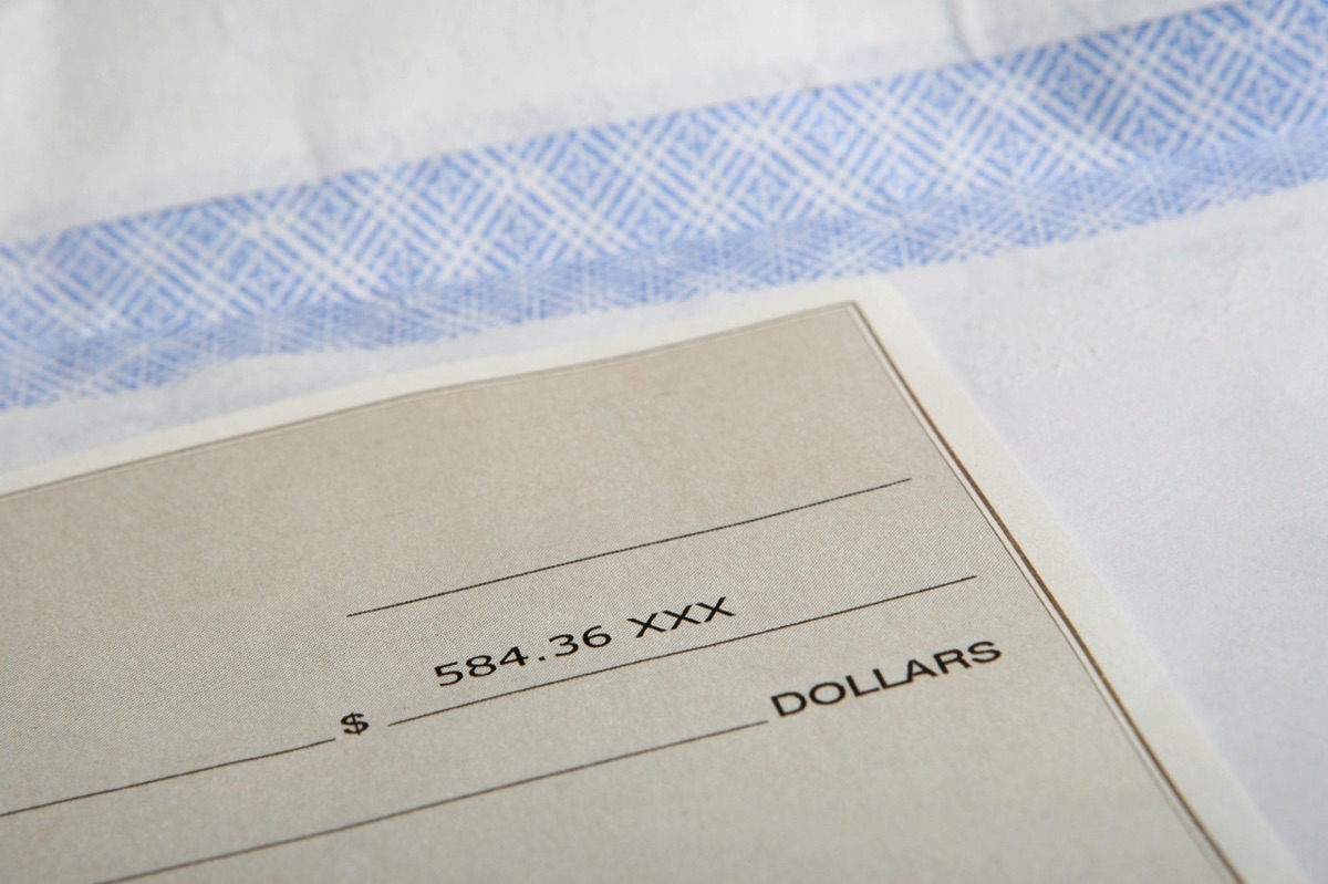 A paycheck made out for $584.36 resting on its envelope