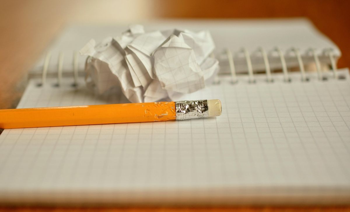 Orange pencil and a crumpled page on a notepad