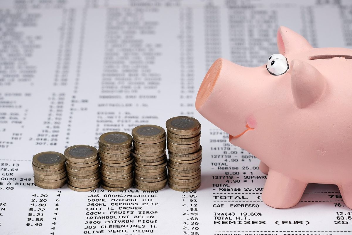 Pink piggy bank beside stacked coins on a printed receipt
