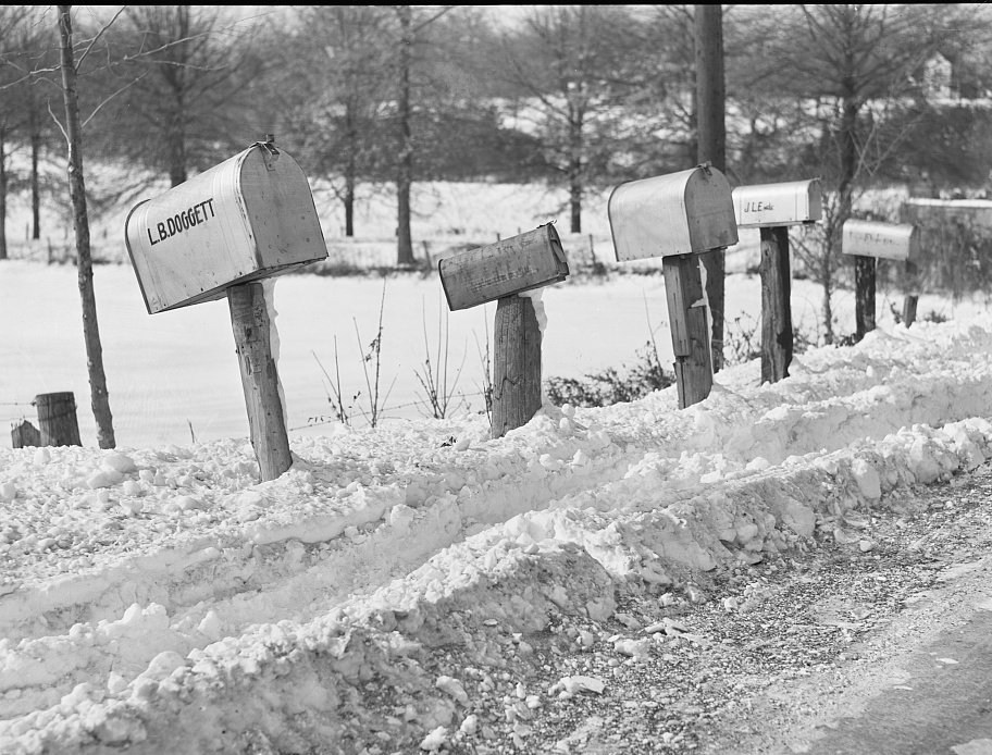 Row of rural mailboxes on wooden posts beside a snowy road, Maryland, 1940
