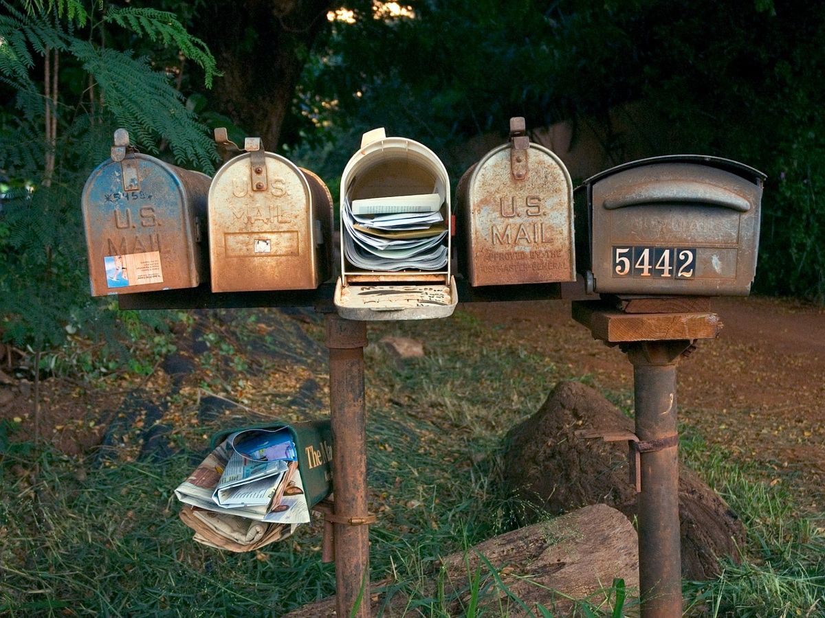 Row of rural mailboxes, one stuffed with mail