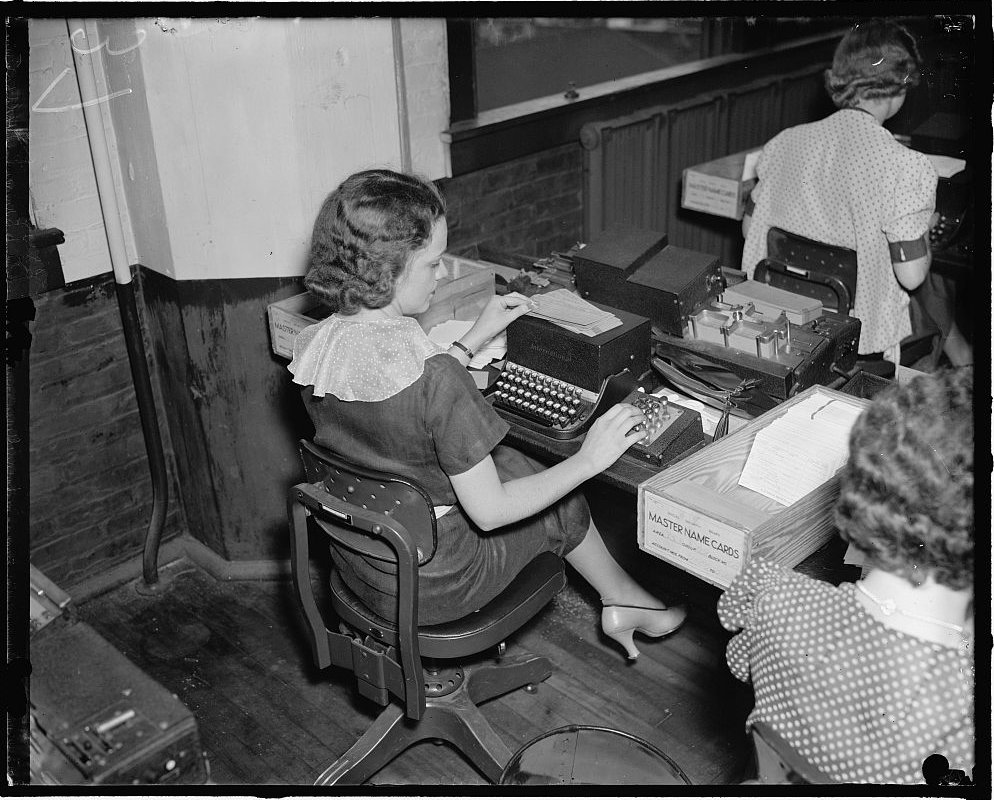 Clerk at a card-punch machine beside a box labeled Master Name Cards, Social Security Administration, 1937