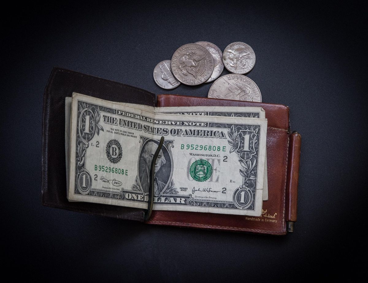 Open wallet holding a few dollar bills and coins
