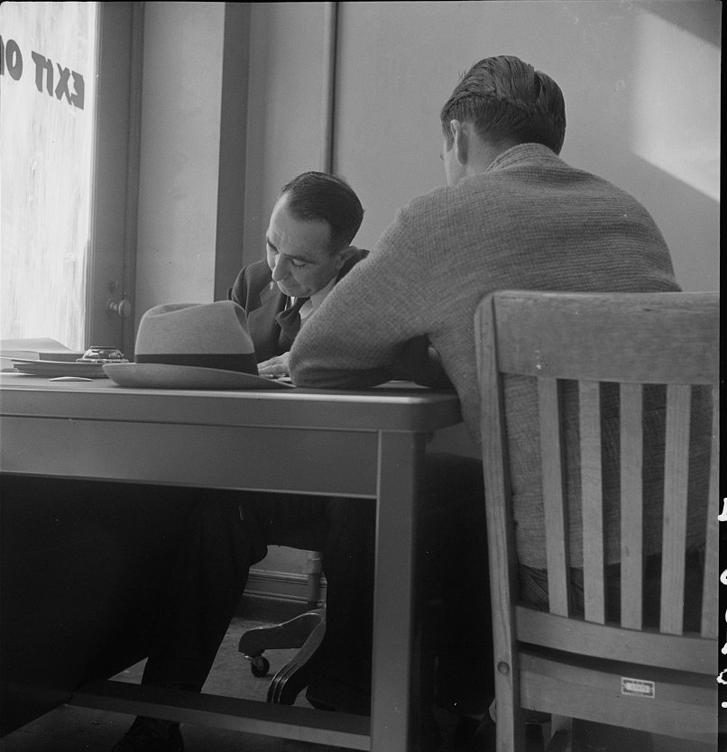 A man across the desk from a claims interviewer at an unemployment office, San Francisco, 1938